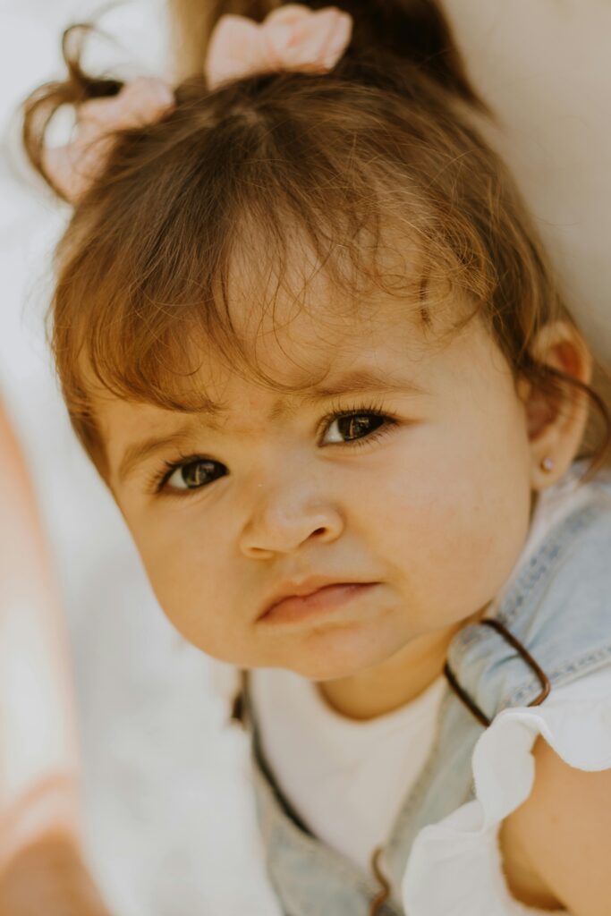 Adorable baby girl with pigtails and denim outfit, conveying emotions, outdoors in São Paulo.